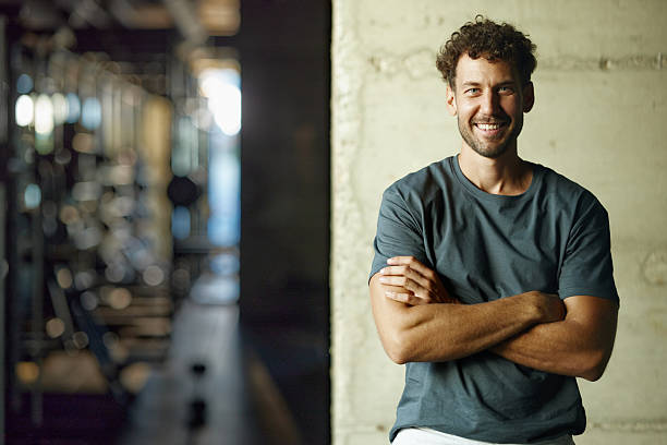 happy athletic man with crossed arms against the wall in a gym